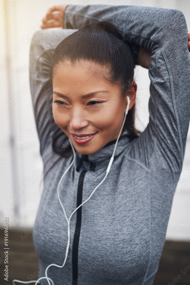 戴着耳机跑步前伸展身体的健康亚洲年轻女性