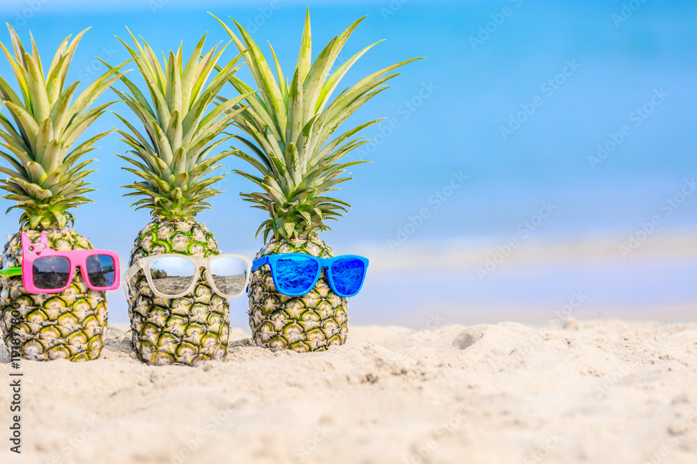 海滩上的菠萝与绿松石的大海相映成趣。戴着时尚的镜面太阳镜。热带