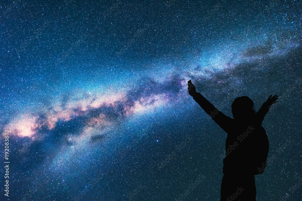 银河系，一个快乐女人的侧影，背着背包，晚上举起双臂。太空背景