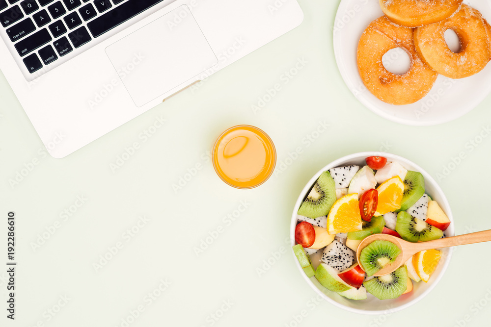 Healthy business lunch in office, fruit salad bowl near laptop on white background. Organic meal and