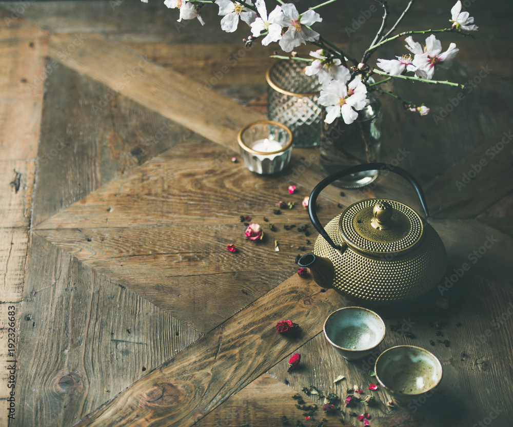 传统的亚洲茶道安排。金铁茶壶、杯子、蜡烛和杏仁花弗洛