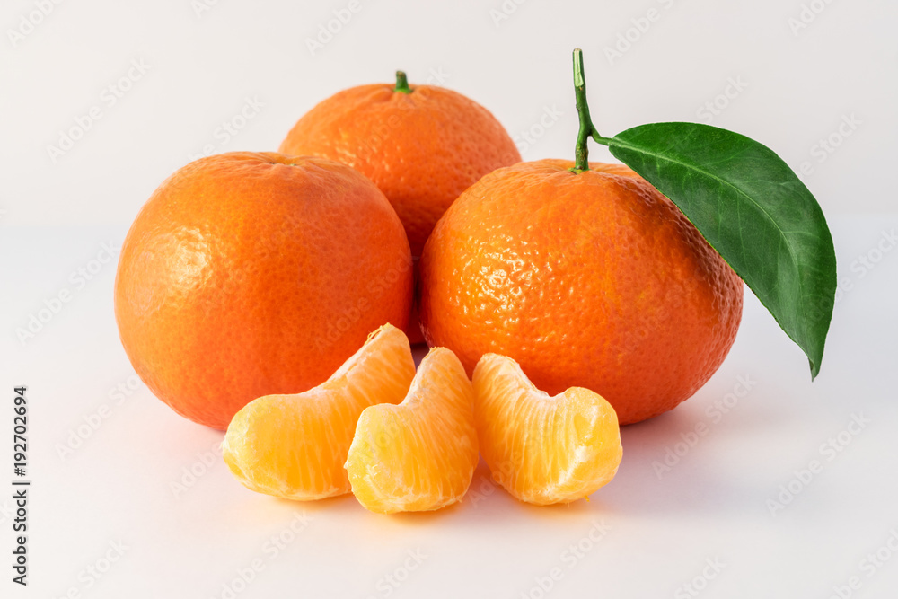 完整的橘子或曼陀罗橙色水果和在白色背景上分离的去皮部分