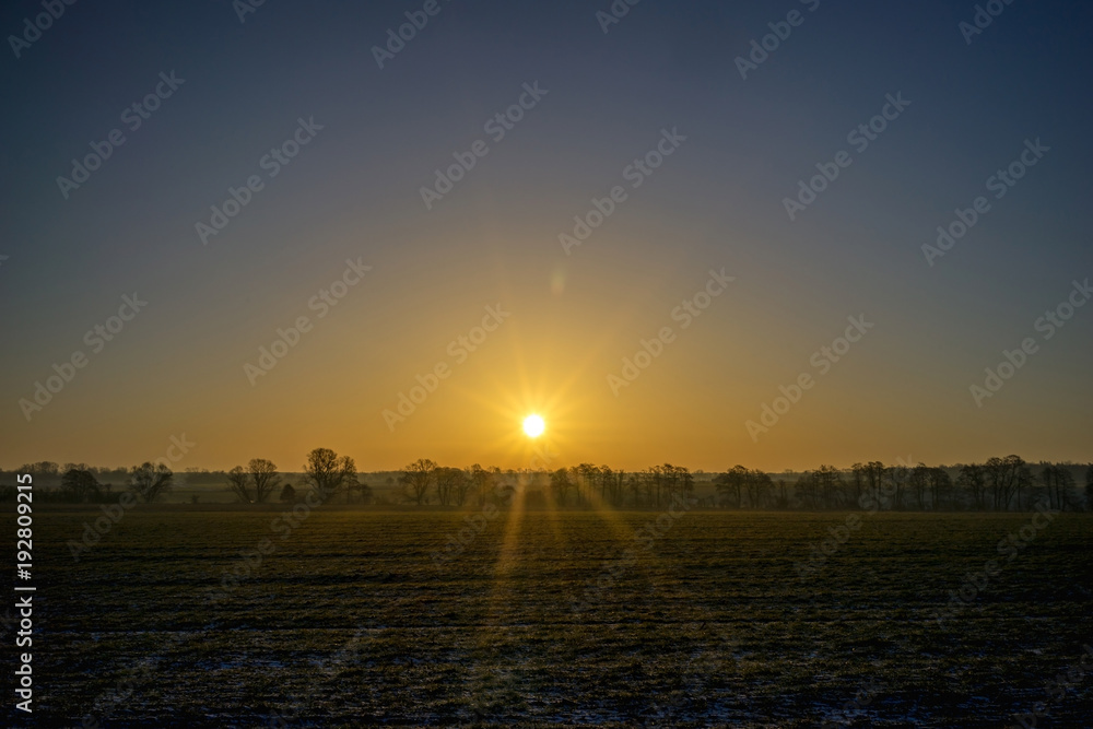 Sonnenaufgang hinter einem Feld