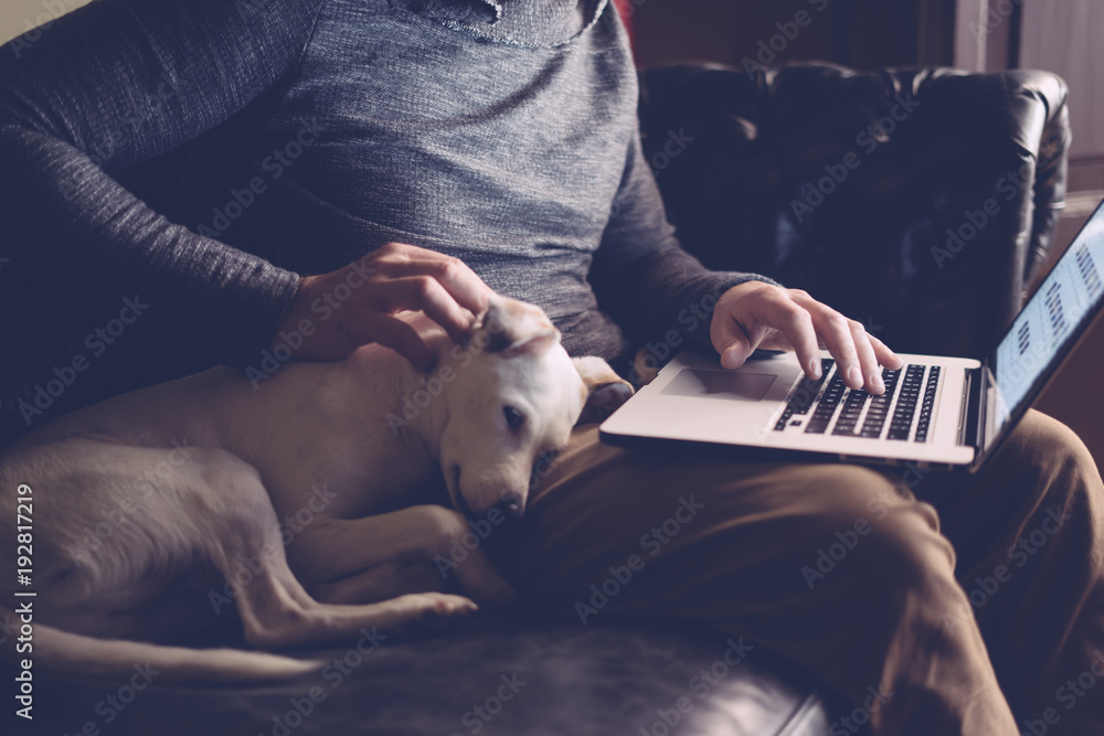 男人带着他的狗和笔记本电脑在家