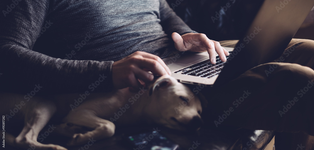 男人带着他的狗和笔记本电脑在家
