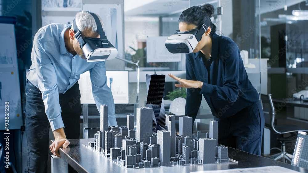 Male and Female Architects Wearing  Augmented Reality Headsets Work with 3D City Model. High Tech Of