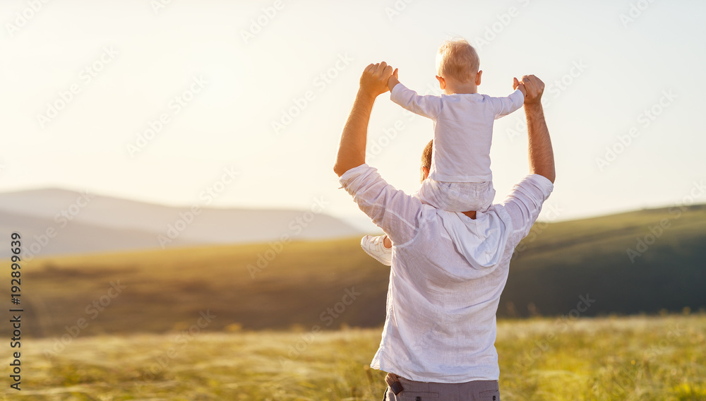 父亲节。快乐的家庭父亲和蹒跚学步的儿子在日落时在大自然中玩耍和欢笑