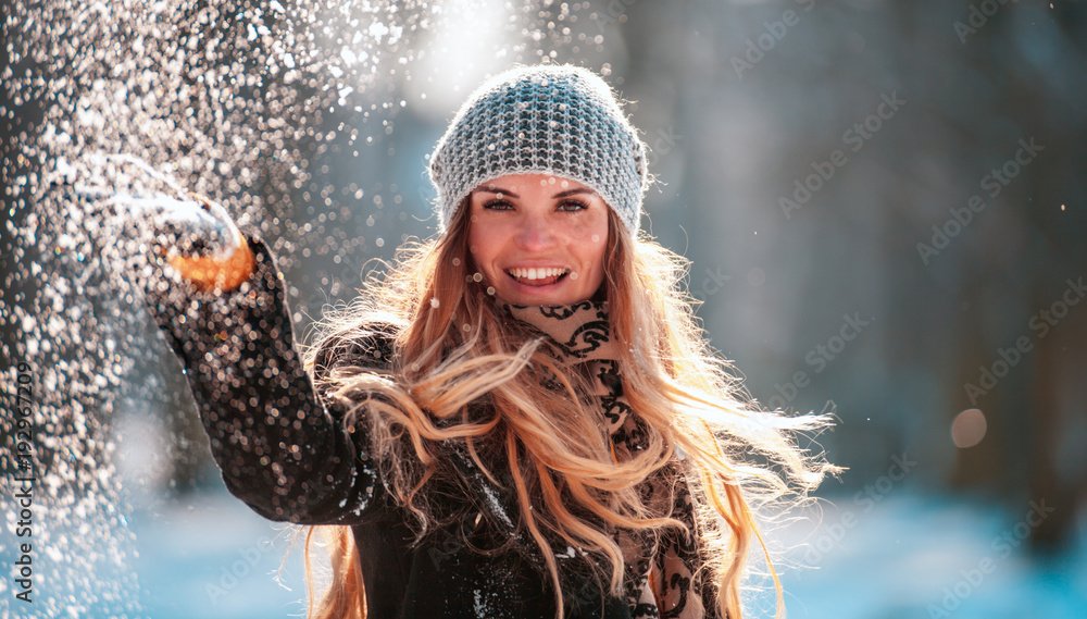 微笑的年轻女子看着镜头向空中扔雪