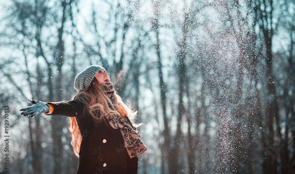 阳光明媚的冬日，微笑的女人向空中扔雪