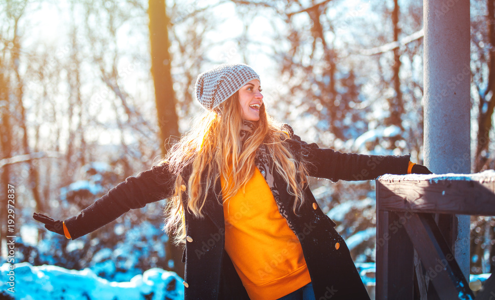 阳光明媚的冬日公园散步时面带微笑的年轻女子