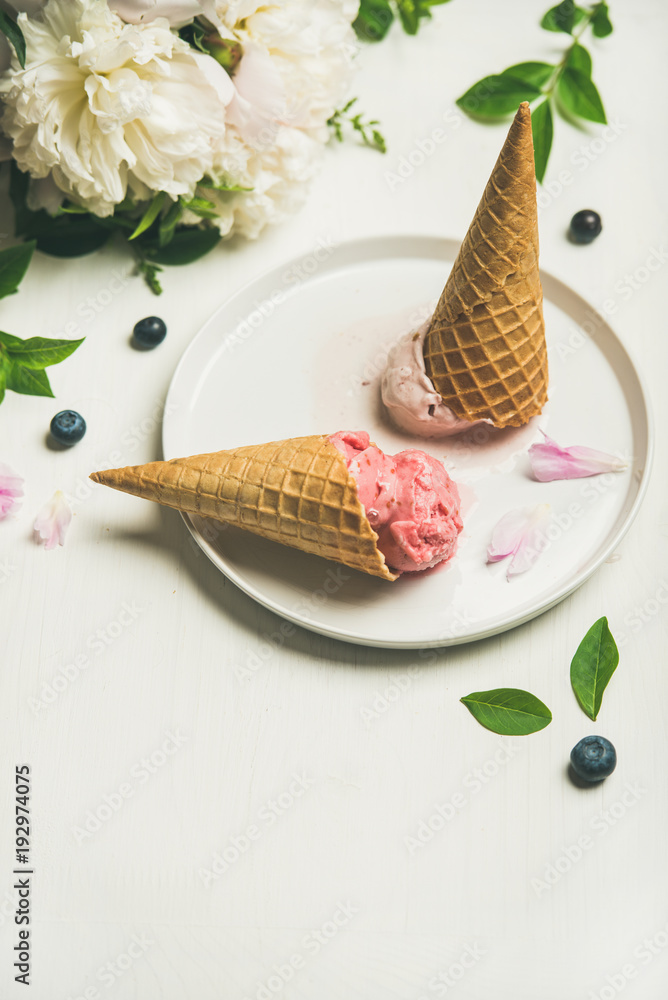 粉红色草莓和椰子冰淇淋勺、甜甜筒和牡丹花在盘子里