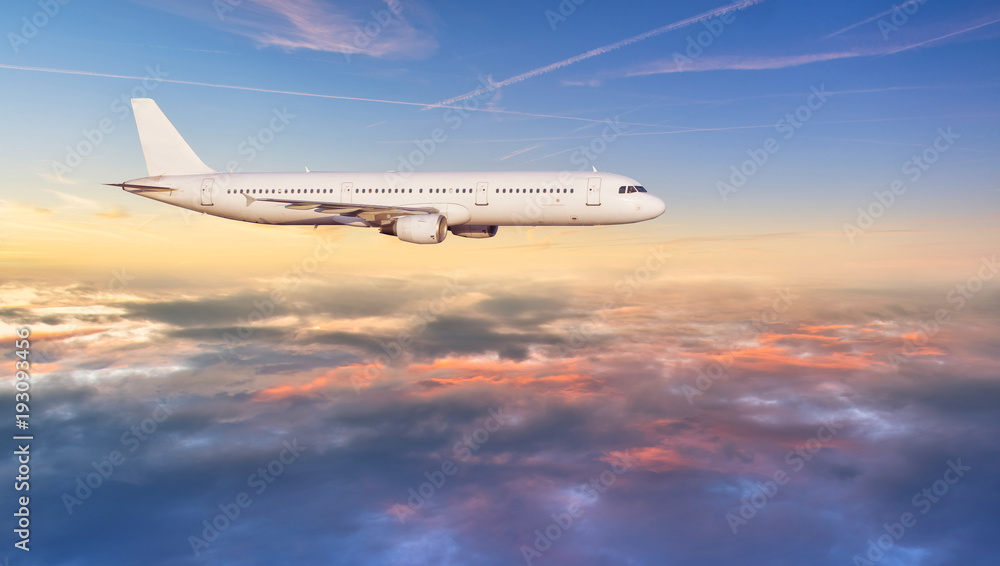 飞机喷气式客机在美丽的日落中飞越云层。
