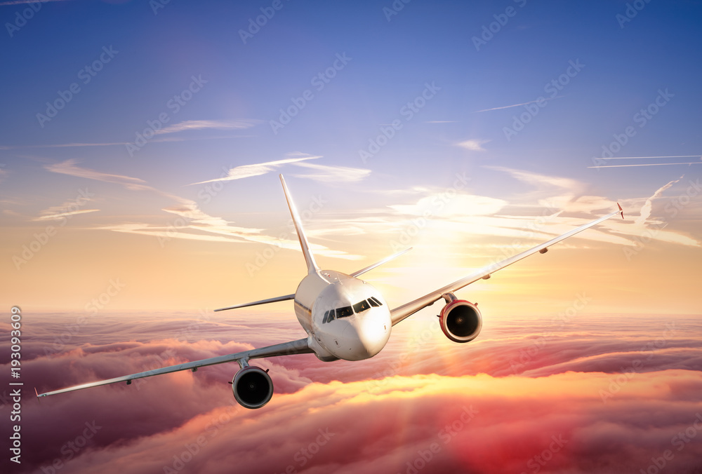 飞机喷气式客机在美丽的日落中飞越云层