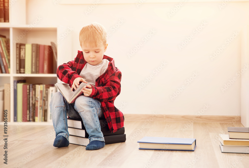 三岁的孩子坐在家里的书中间