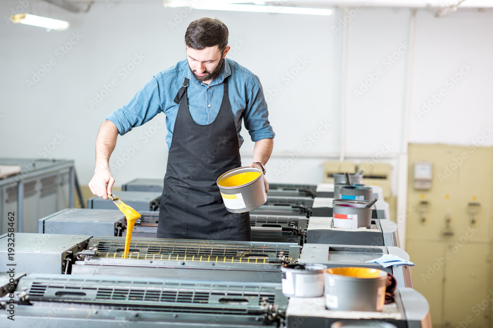 印刷制造厂的打字机将黄色油漆填充到胶印机中
