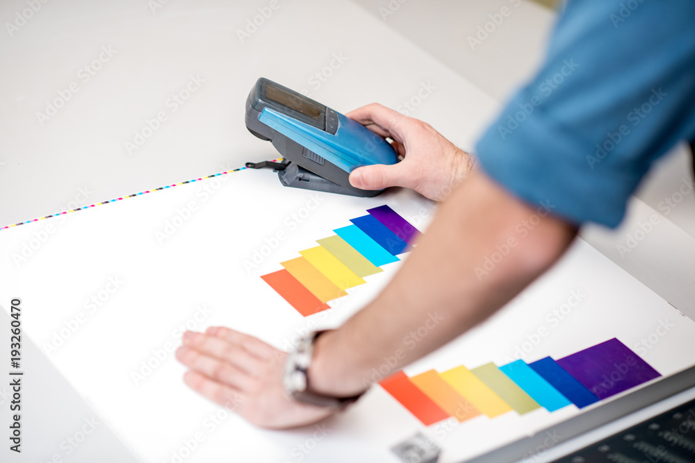 在打印计划的操作台上使用光谱仪工具测量纸质打印上的颜色