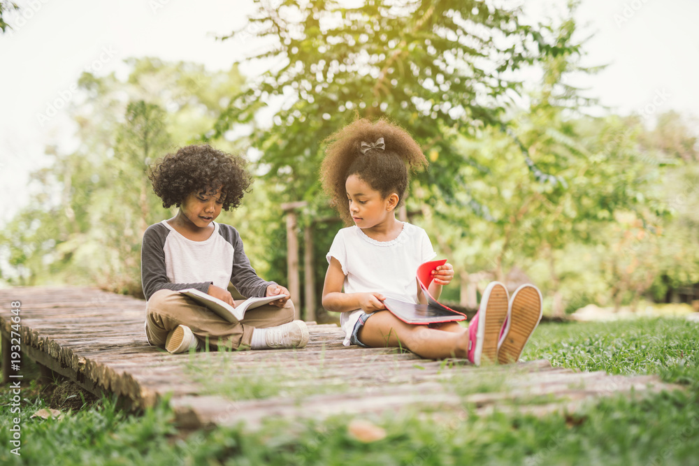 非洲小女孩与朋友在绿色尖刺之间的草地花园读书阅读教育c