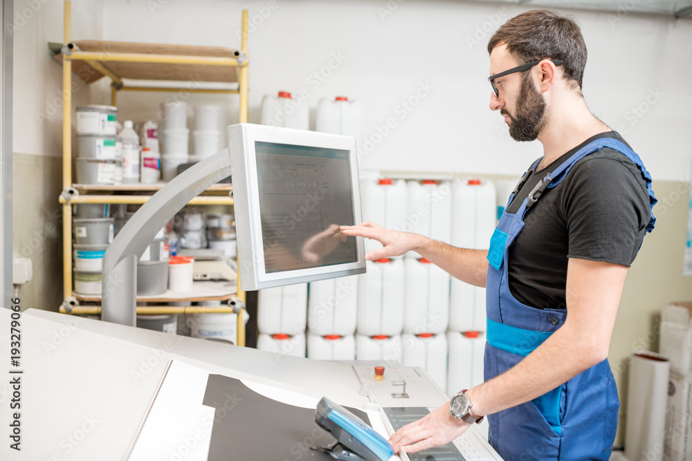 在印刷厂的操作台上，人在设置印刷机触摸屏幕