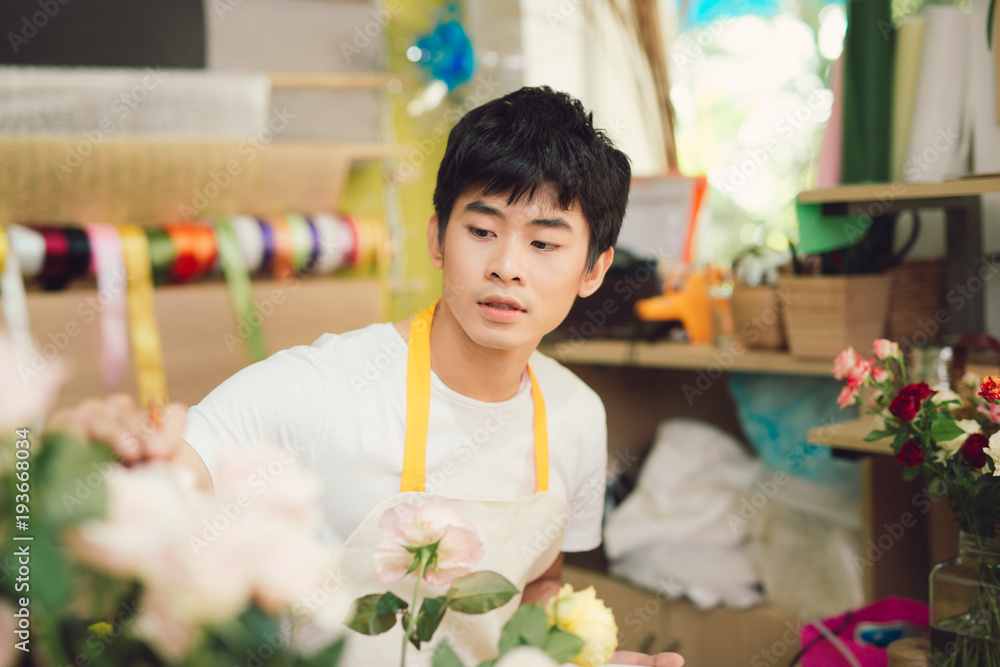 微笑的年轻亚洲花店男子在花店制作花束