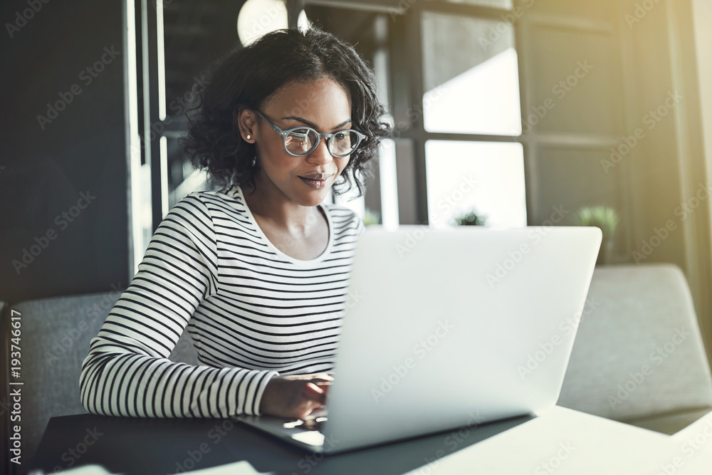 年轻的非洲妇女独自坐在笔记本电脑上工作