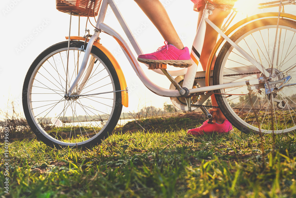 公园日落时骑自行车的近距离腿部女性