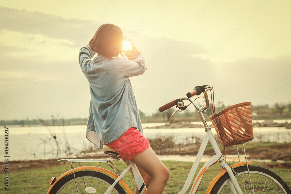 骑自行车的亚洲年轻女子看手框日落