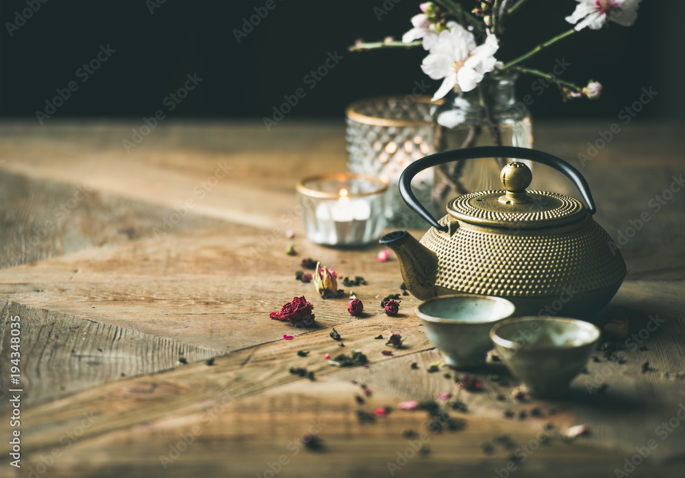 Traditional Asian tea ceremony arrangement. Golden iron teapot, cups, candles and almond blossom flo