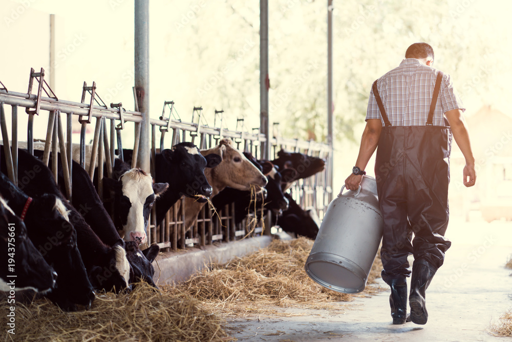 农民亚洲人在他的农场上拿着一容器牛奶。走出农场