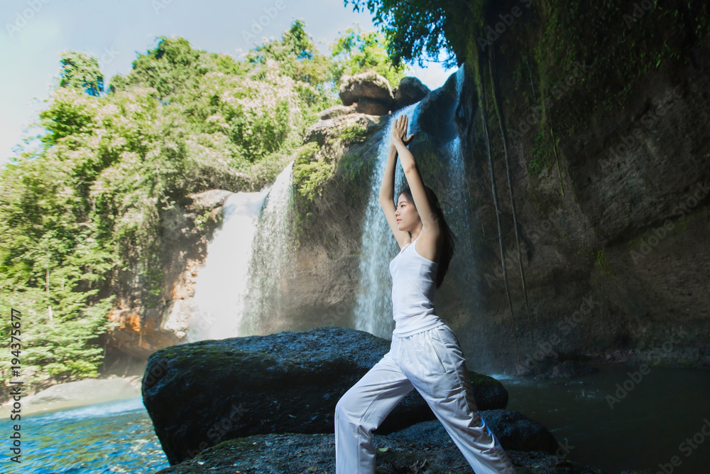 Woman doing yoga and meditation at the waterfall