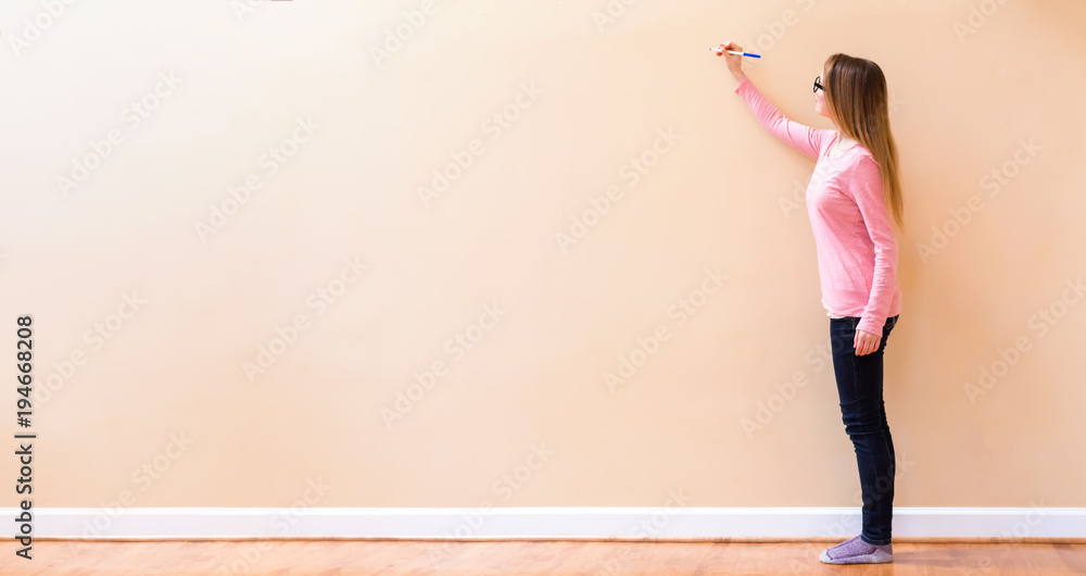 年轻女子在一堵敞开的大墙上画东西