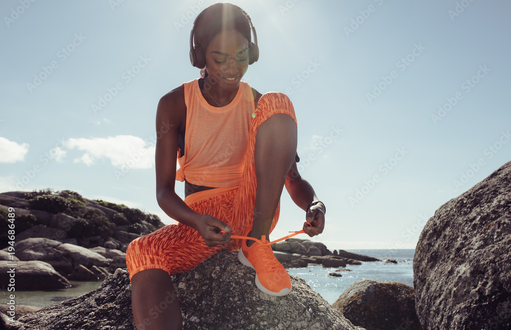一名女子在海滩跑步前系鞋带