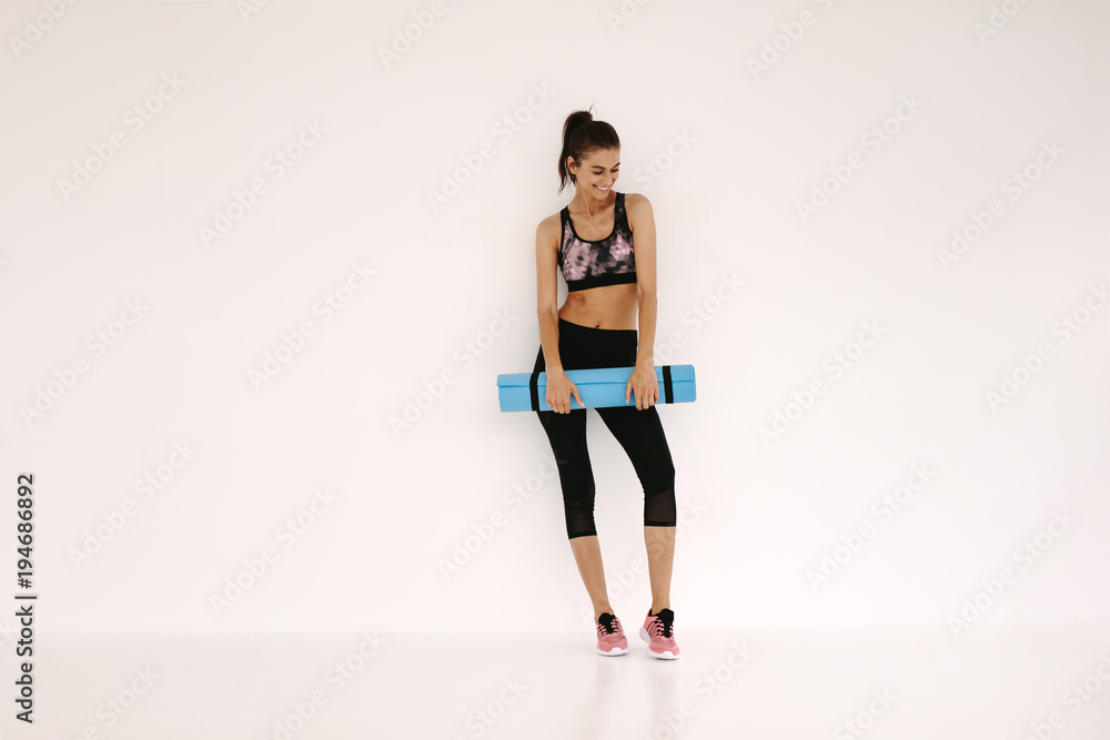 Sportswoman with yoga mat in fitness studio