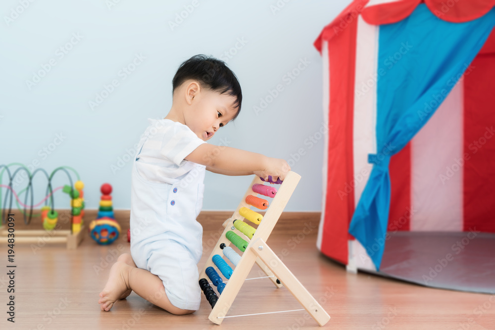 亚洲男婴学会数数。可爱的孩子在玩算盘玩具。小男孩在室内玩得很开心。