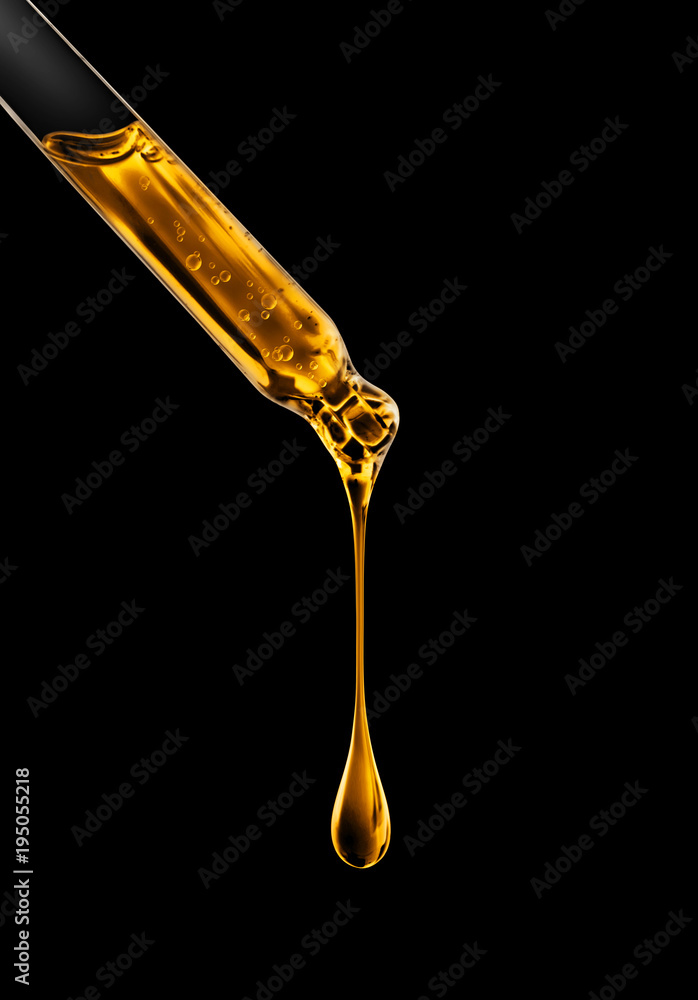 Cosmetic pipette with oily drop closeup on black background