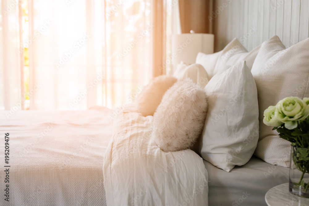 美丽的床上有一个柔软的枕头，舒适的卧室，阳光来自窗户内部概念