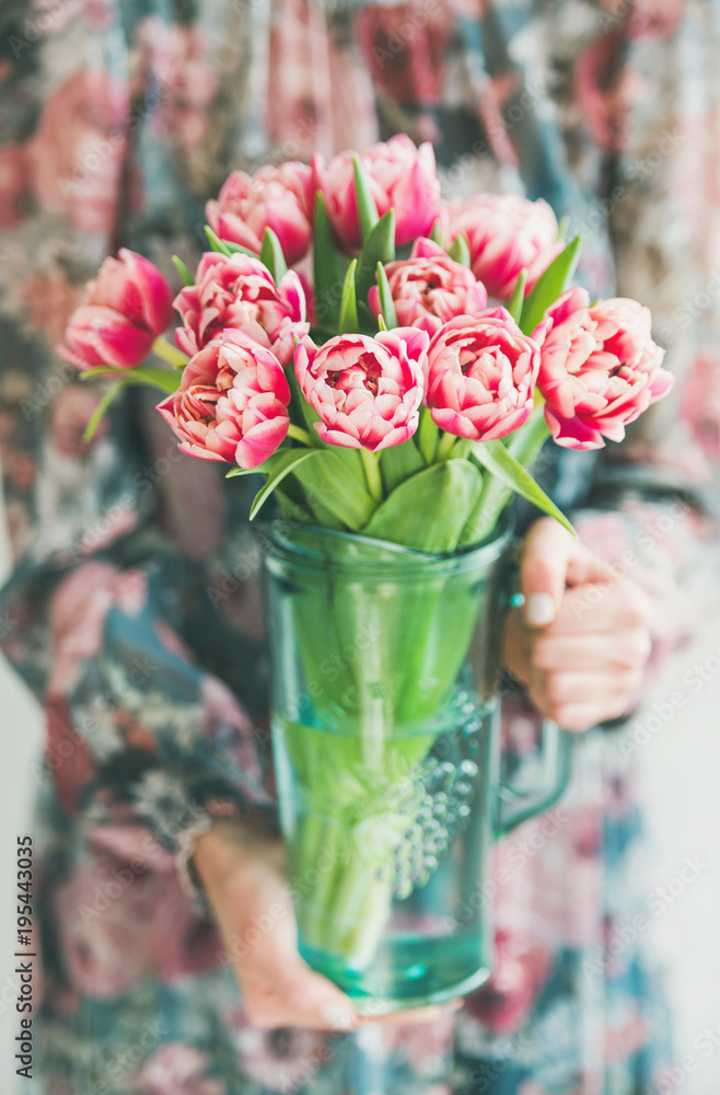 春季插花。穿着彩色丝绸连衣裙的女人手里拿着一束新鲜的粉红色郁金香。弗洛里