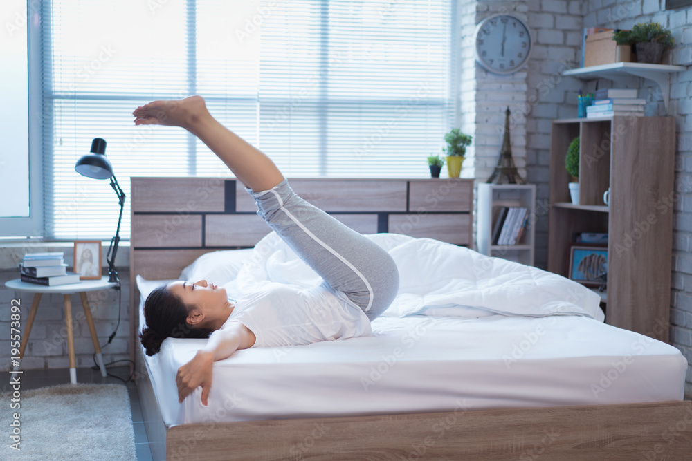亚洲女性早上在床上锻炼，她感觉神清气爽。她做了平板运动
