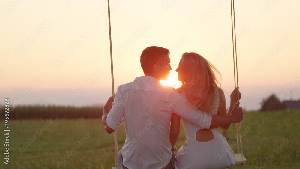 LENS FLARE CLOSE UP: Swaying young couple kissing in summer sunset under a tree