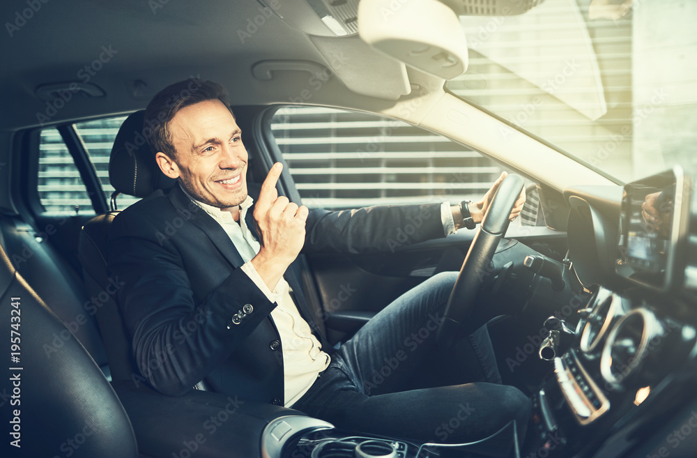 Smiling businessman navigating through traffic in his car