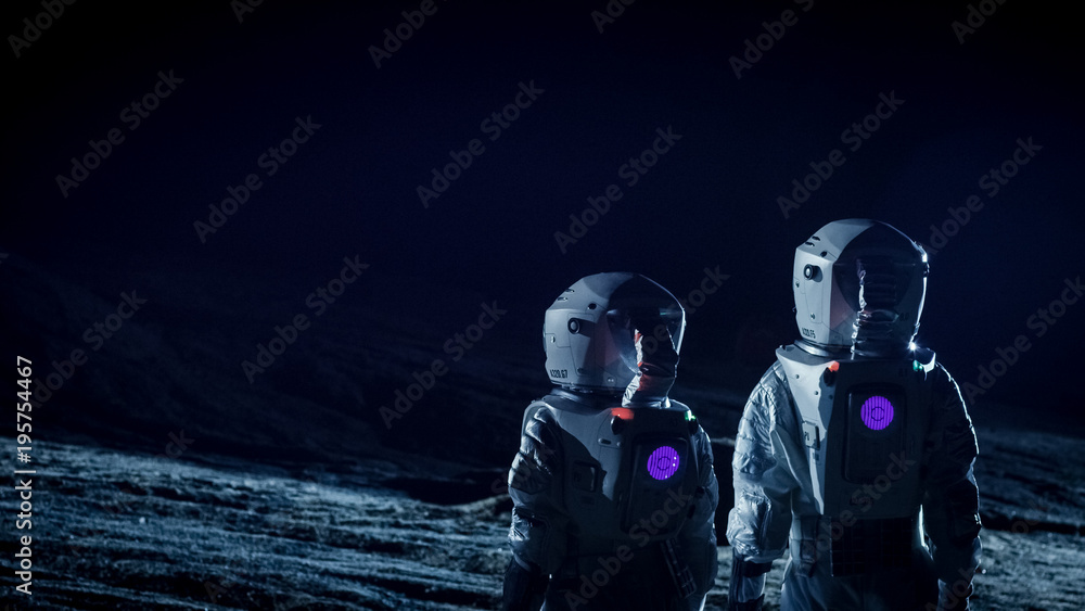 两名身穿太空服的宇航员站在外星上看黑暗的天空。太空旅行，可居住
