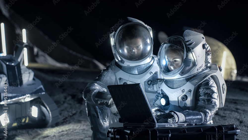 Two Astronauts Wearing Space Suits Work on a Laptop, Exploring Newly Discovered Planet, Send Communi