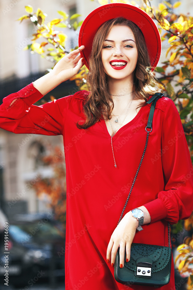 美丽快乐的微笑女孩，戴着时尚的红色帽子，穿着连衣裙，戴着手表，带着绿色的小袋子