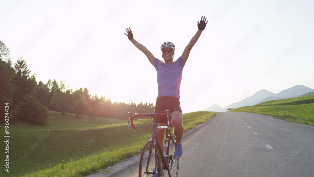 太阳耀斑：职业自行车手在获胜后兴高采烈地骑着公路自行车，没有双手。