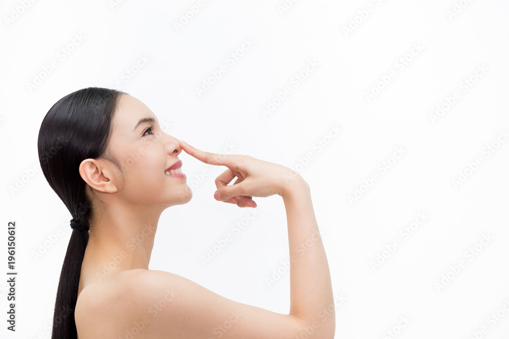 年轻漂亮的女人在孤立的白色背景上用指尖触摸她的鼻子。