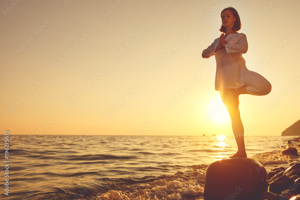 女子在日落海滩练习瑜伽冥想