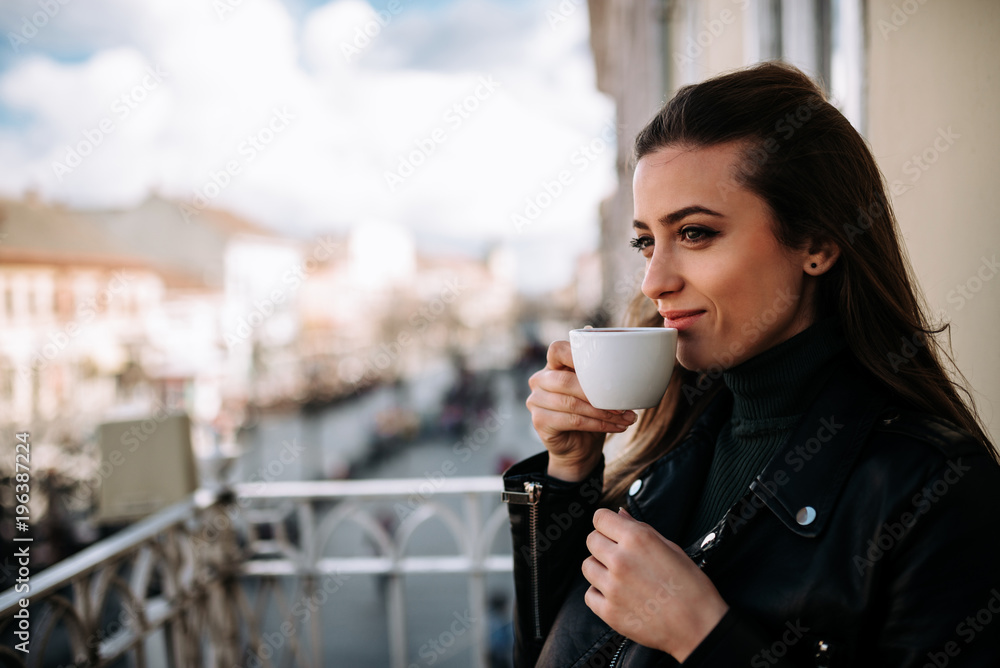 女人在露台上喝咖啡的特写图片。