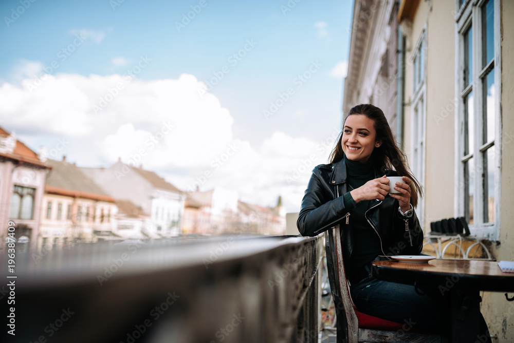 女孩坐在老城区的阳台上，喝咖啡。