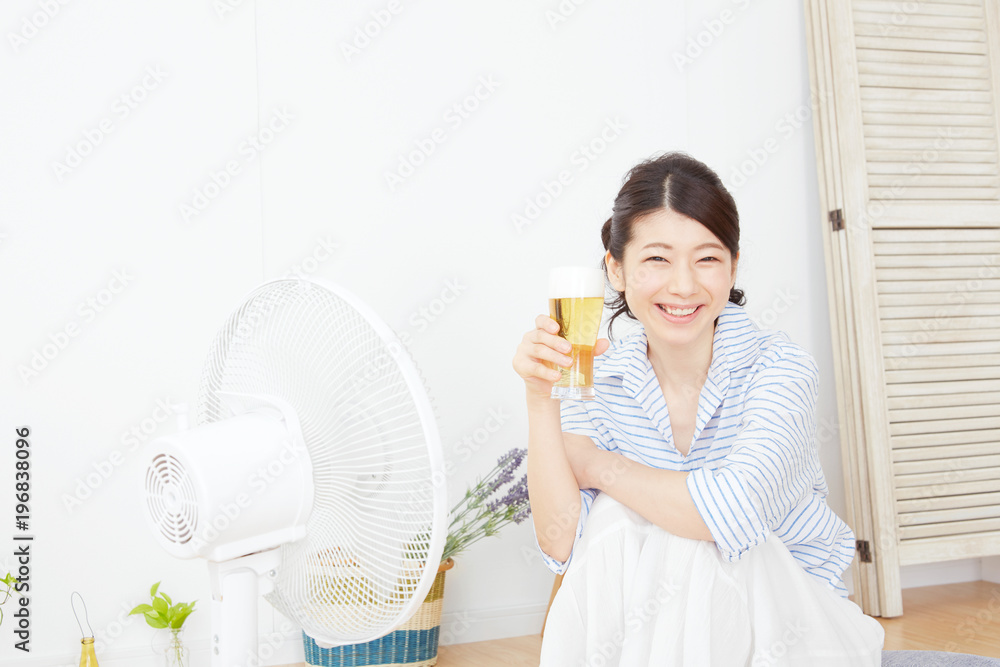 扇風機にあたりながらビールを飲む女性