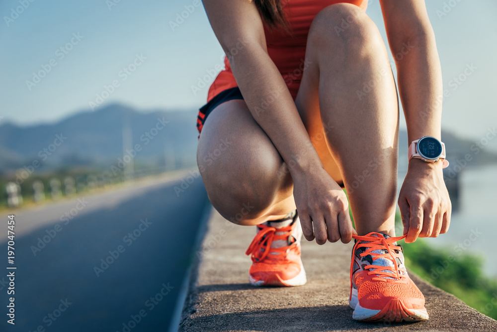 一名亚洲女运动员在水泥路上慢跑，她正在温暖自己的身体，缓解自己的紧张情绪