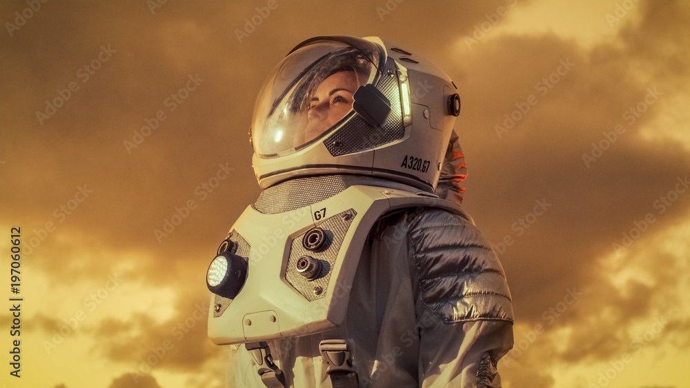 身穿太空服的女宇航员环视外星的照片。红色和橙色行星西米拉